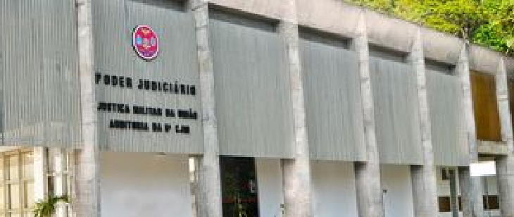 Fachada da 6ª CJM, que atende Bahia e Sergipe. Prédio térreo com colunas verticais e fachada branca com detalhes em concreto. Há placas institucionais e vegetação ao redor.